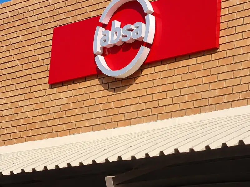 Illuminated three-dimensional Absa logo sign on a brick building facade
