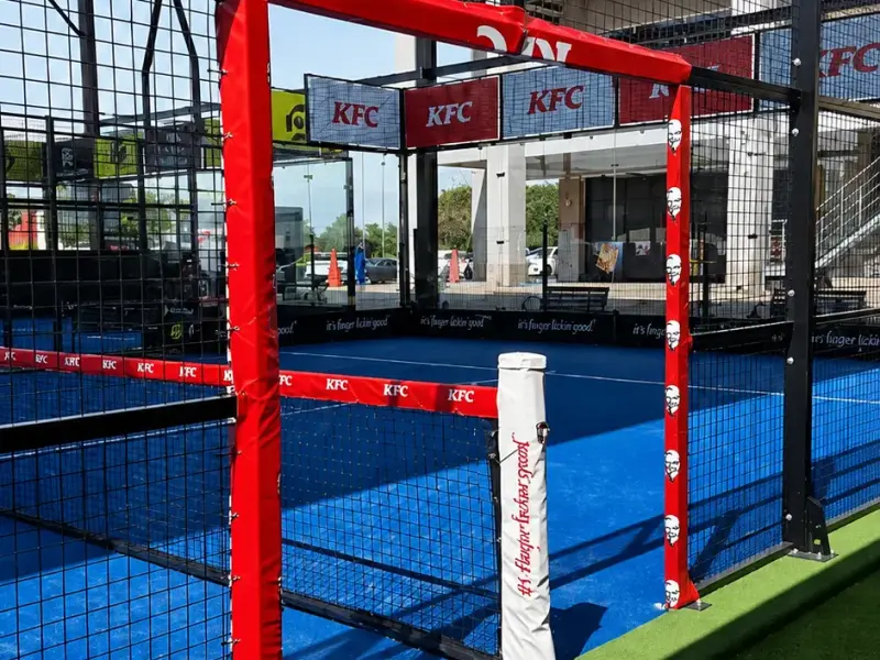 KFC-branded padel court with printed perimeter boards and post padding