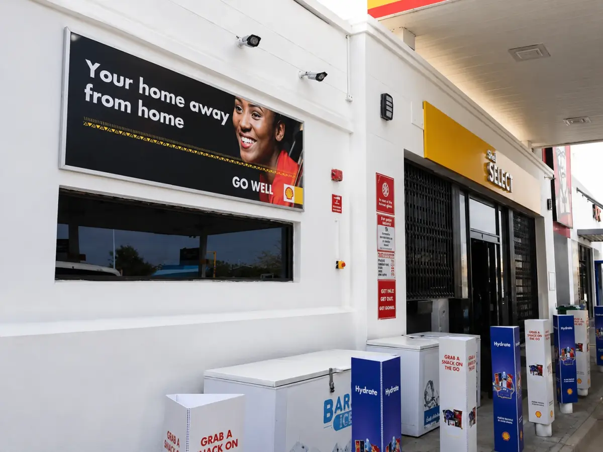 Shell forecourt shop with an illuminated Go well lightbox and branded bollards and freezers